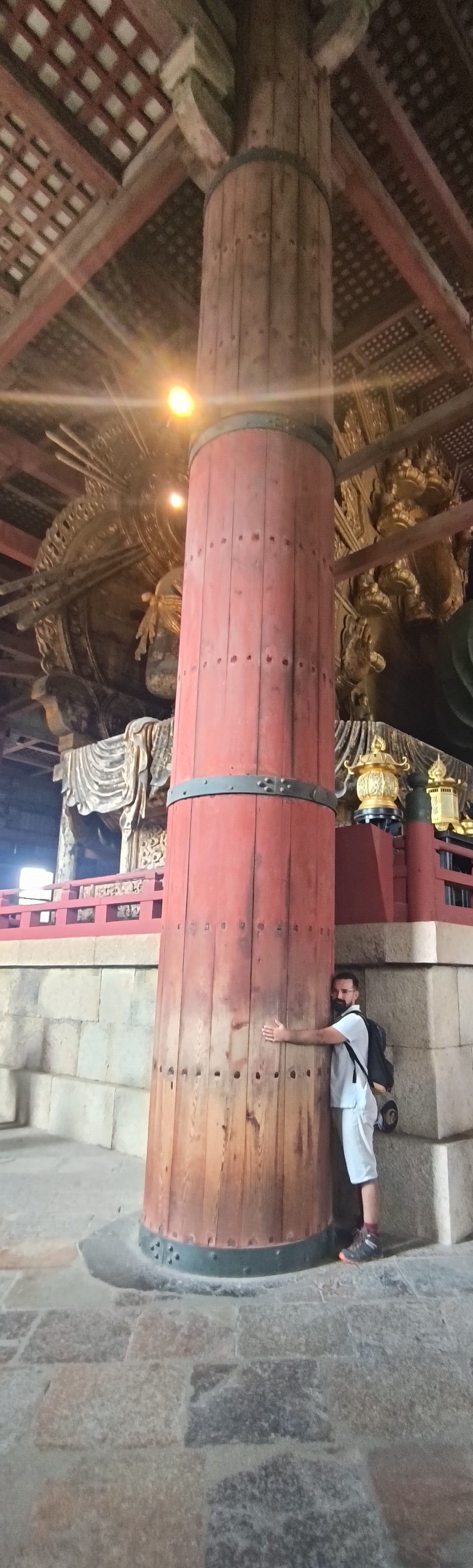 Gabriel Santos enlaçant un pilier en bois d'un temple japonais